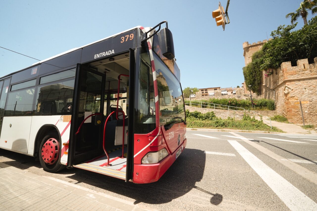 Autobús vermell amb la porta oberta davant d'un castell.