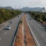 Autopista amb cotxes i una central nuclear al fons.